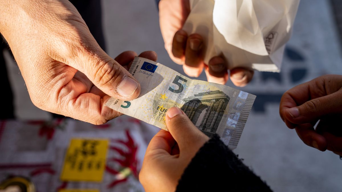 A costumer hands over a five euro banknote at a street stall in Brescia, Italy, on Thursday Nov. 16, 2023. A possible downgrade of Italy to junk this week would be hugely symbolic, potentially consequential  and very controversial. Photographer: Francesca Volpi/Bloomberg via Getty Images