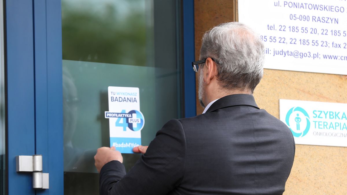 Profilaktyka 40 Plus. Minister zdrowia Adam Niedzielski nakleja informację przed Centrum Medycznym Judyta w Raszynie.