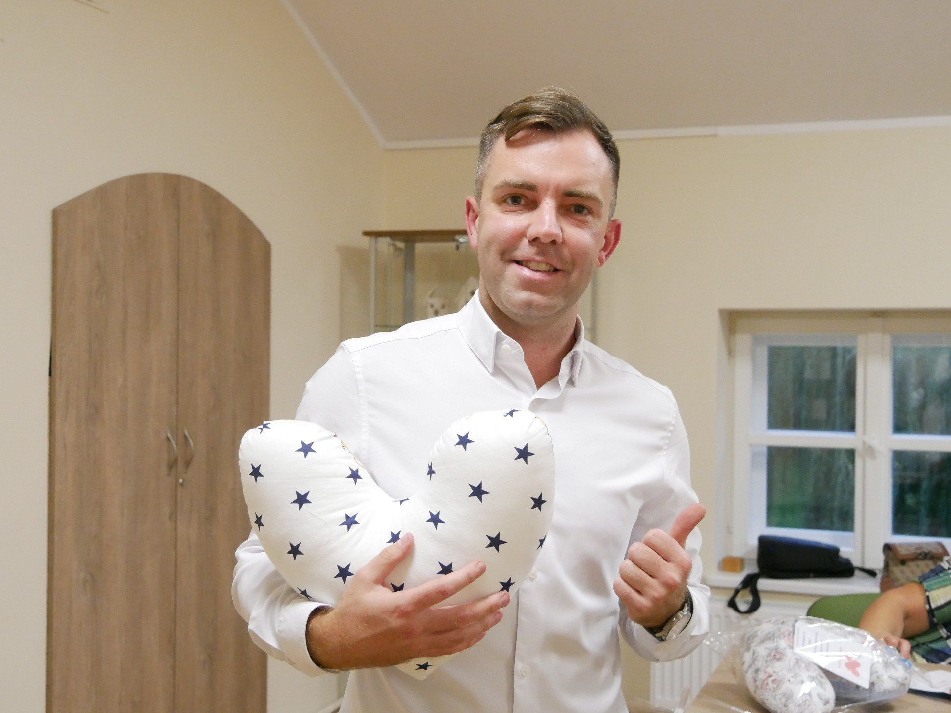 Tomasz Pocztowy wraz z jedną z poduszek, które zostaną przekazane dla kobiet po mastektomii. 