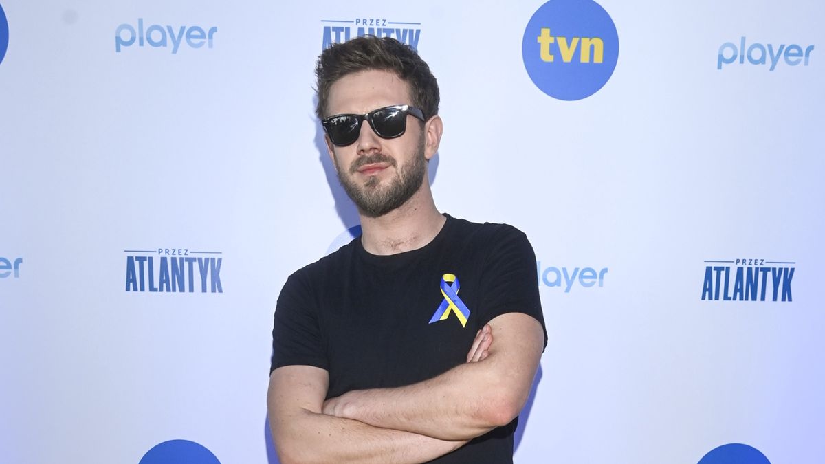 scena z: Antoni Królikowski, SK:, , fot. Kurnikowski/AKPAbroda, marzec 2022, okulary czarne, okulary z czarnymi oprawkami, spodnie czarne, Spotkanie z uczestnikami programu "Przez Atlantyk", sylwetka, sztyblety, koszulka czarna, Antoni Królikowski