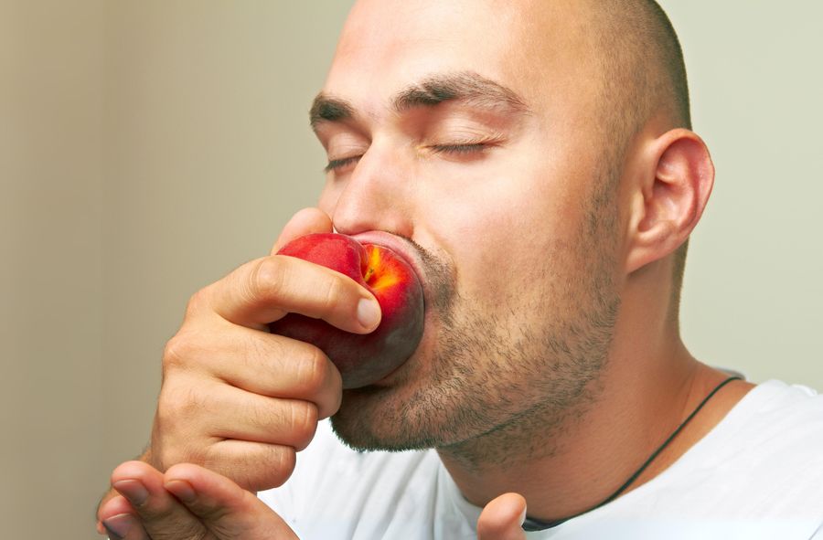 Mężczyzna jedzący brzoskwinię