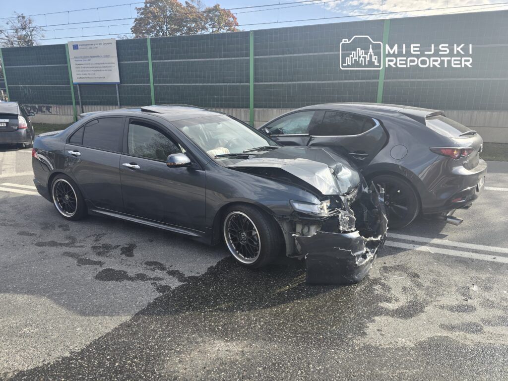 Dwa uszkodzone samochody na parkingu; szary sedan z rozdartym przodem i ciemny hatchback obok.