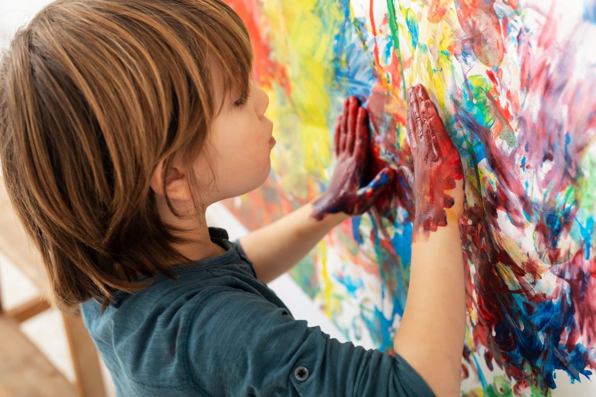 Dziecko maluje obraz własnymi dłońmi.