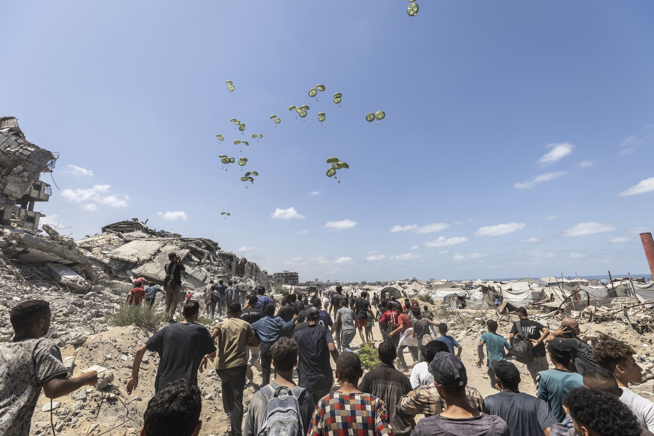 Palestyńczycy biegnący w stronę zrzucanej żywności.