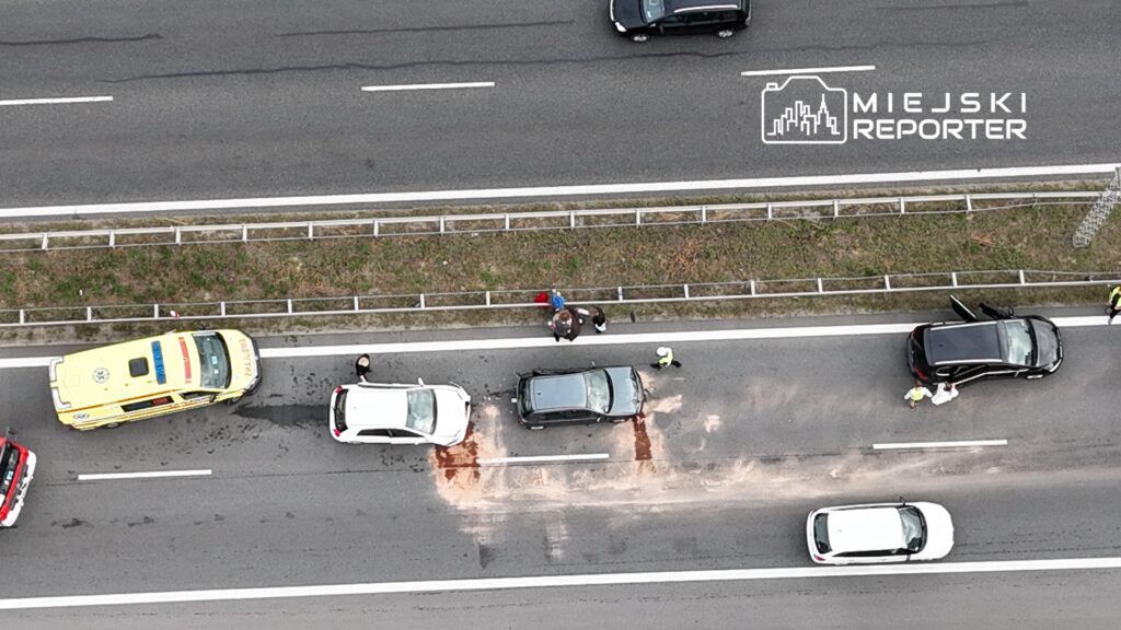 Na drodze ekspresowej zatrzymane dwa samochody, obok nich pracownicy służb ratunkowych oraz policja.