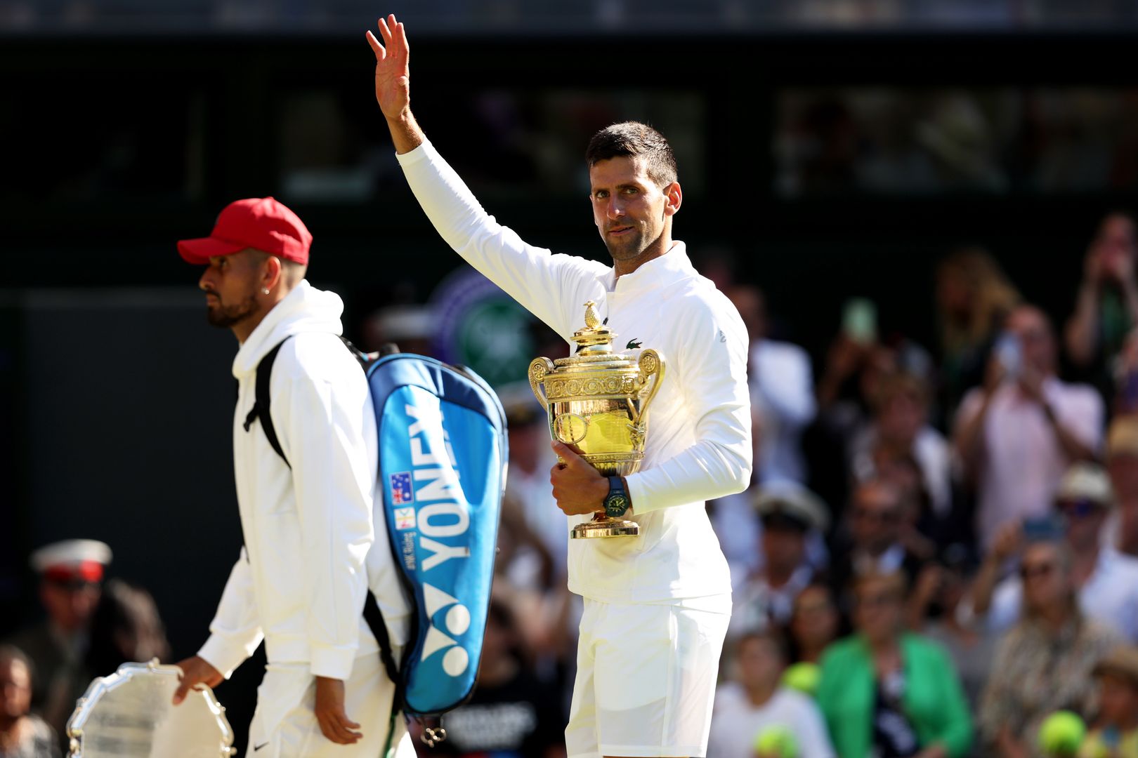 LONDON, ENGLAND - JULY 10: Novak Djokovic of Serbia waves goodbye to the crowd as he walks off court whilst holding the trophy following his victory against Nick Kyrgios of Australia during their Men's Singles Final match on day fourteen of The Championships Wimbledon 2022 at All England Lawn Tennis and Croquet Club on July 10, 2022 in London, England. (Photo by Clive Brunskill/Getty Images)