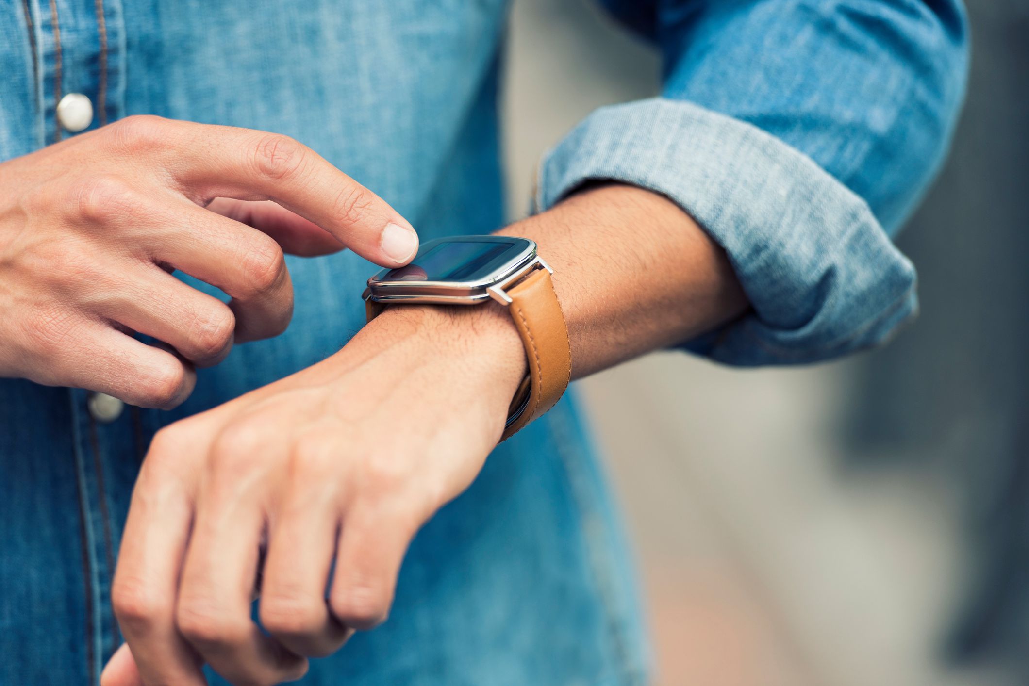 Man in the street using his smart-watch app. Urban background. Close-up hands 