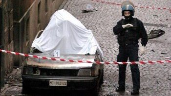 Włoski policjant obok spalonego samochodu