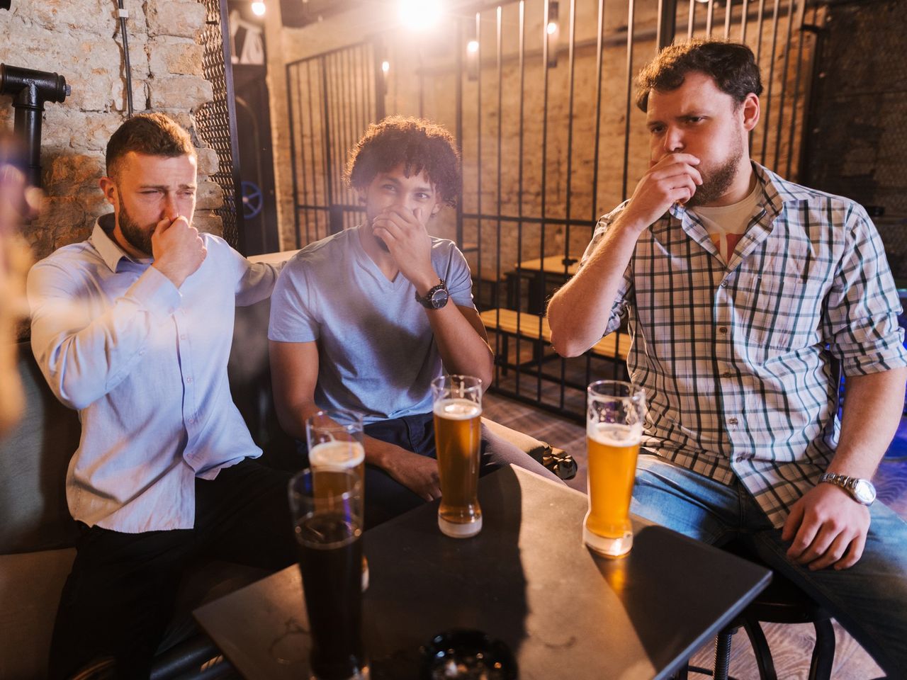 Man smoking in pub and his friends coughing. Anti smoking concept.