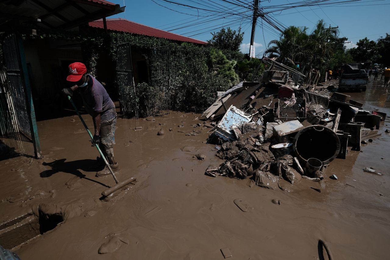 Skutki przejścia huraganu Eta w Hondurasie. Mieszkaniec usuwa błoto z ulicy obok sterty gruzów po ogromnych powodziach wywołanych przez huragan Eta. 11 listopada 2020 r., La Lima, Honduras.