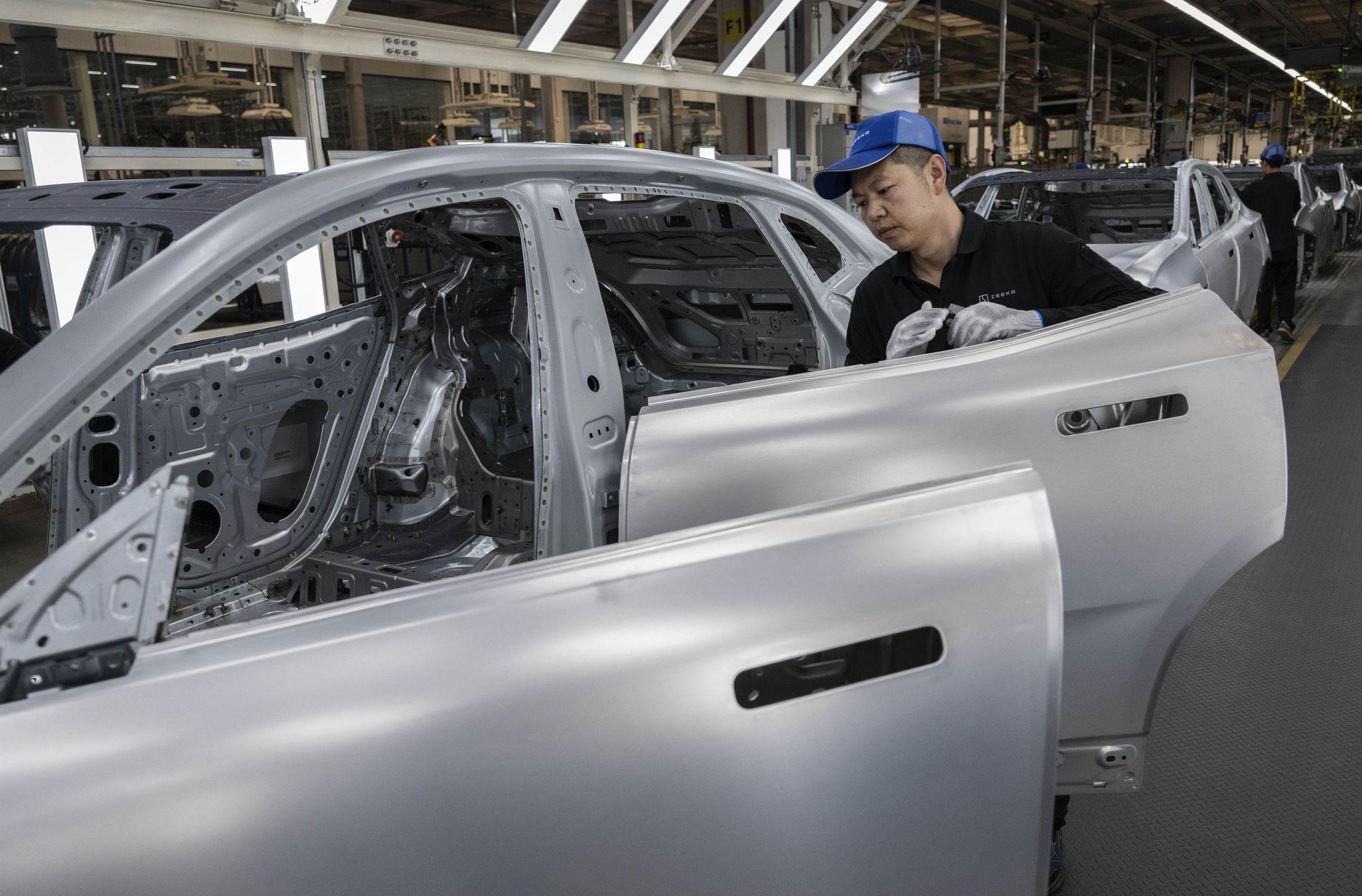 NINGBO, CHINA - MAY 29: A worker assembles a car frame on the production line for electric vehicle maker Zeekr at its factory on May 29, 2025 in Ningbo, China. China's automakers account for nearly two-thirds of global sales of electric vehicles and exports more vehicles overseas than any other country. Zeekr, a pure-electric brand aimed at the luxury market, has seen sales growth in the highly competitive Chinese market and is furthering its expansion into Asia, the Middle East, Latin America, and parts of Europe. The company's plans to enter the US market has faced hurdles due to tariffs on China made electric vehicles. In 2024, Zeekr delivered more than 220,000 vehicles, according to the company. Zeekr is among several Chinese EV makers building vehicles in automated factories using robotics powered by artificial intelligence alongside human workers. Zeekr is owned by Geely Holdings, which also has ownership stake in a number of foreign brands including Volvo, Lotus, and Polestar. (Photo by Kevin Frayer/Getty Images)