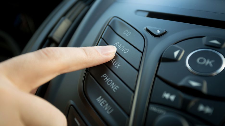 Closeup photo of female finger pressing radio button on car control panel