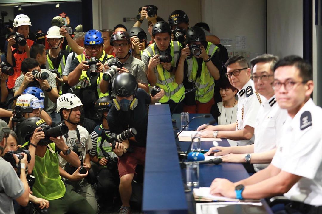 Fotoreporterzy w maskach i kamizelkach protestują przeciwko policji w Hongkongu