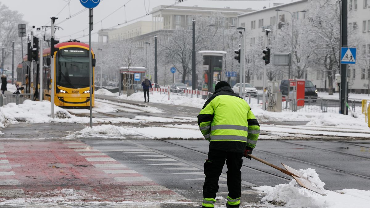 WARSAW, POLAND - 2026/01/28: A man clears snow at a pedestrian crossing in the Praga Pónoc district. Snowfall overnight covered the city streets in Warsaw. Pedestrians and commuters move through fresh snow as winter weather settles in the capital. (Photo by Volha Shukaila/SOPA Images/LightRocket via Getty Images)