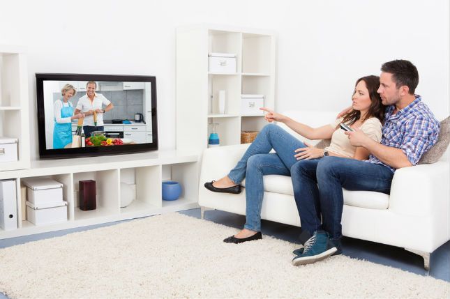 Zdjęcie pary przed telewizorem pochodzi z serwisu Shutterstock
