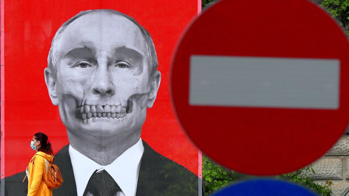 Na zdjęciu po lewej stronie mural przedstawiający Putina-czaszkę, po prawej - znak stop