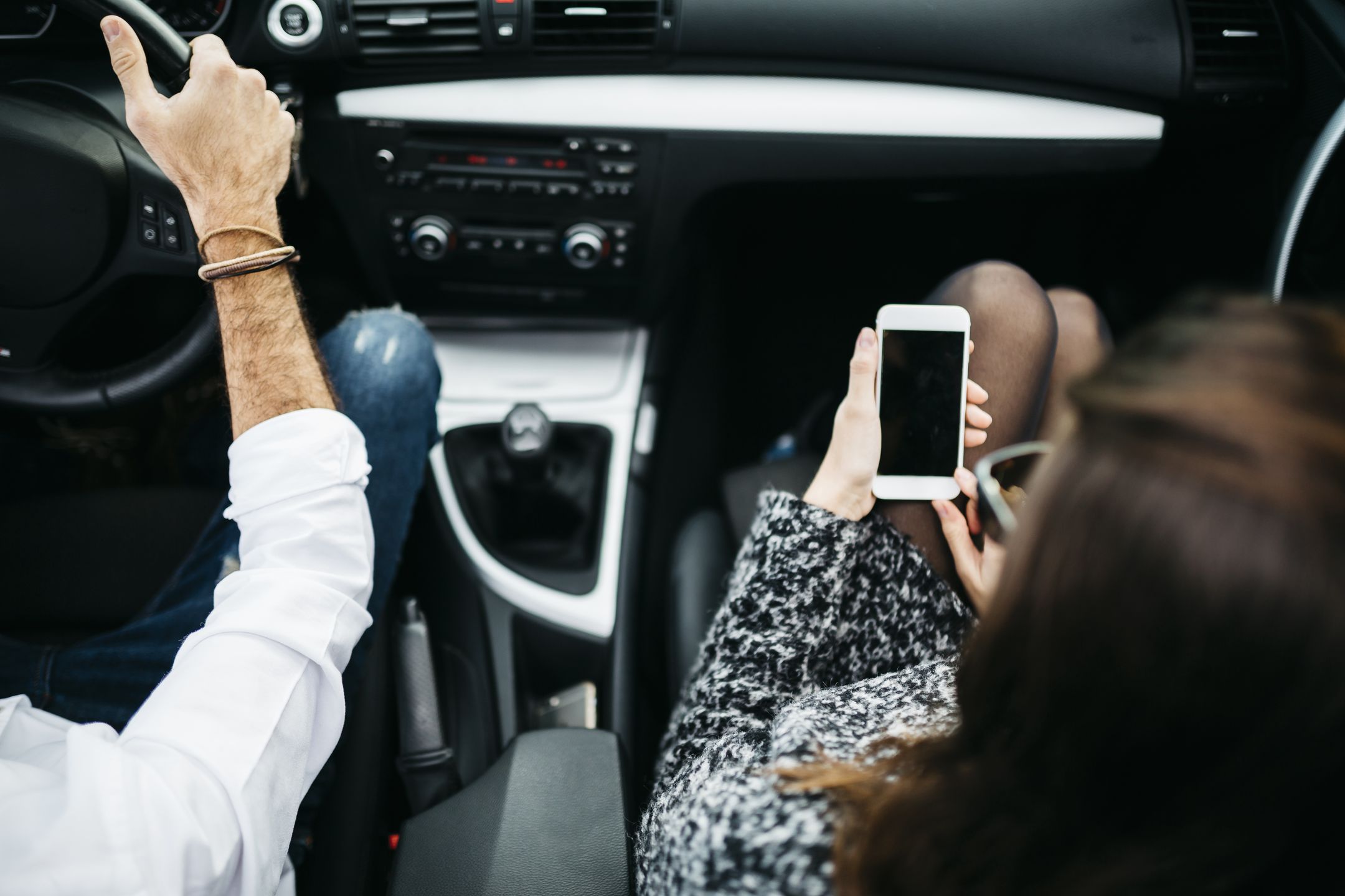 Young couple driving in a car, co driver using smart phoneWestend61transportation, vehicle, motor vehicle, car, driving, car driving, sitting, on the move, Connection, Travel, people, car driver, indoor, elevated view, birds eye view, close up, day, communication, steering, steering wheel, telecommunication, accessibility, Wireless Technology, text messaging, GPS, Differential Focus, Part Of, telephone, mobile phone, Smart Phone, Road Trip, passenger, Adults, woman, young women, man, young man, two people, young adult, 25-29 years, caucasian appearance, Southern European Ethnicity, couple, adult couple, young couple, arm, human hand, Spain
