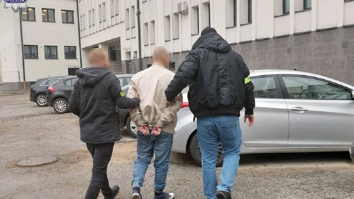 Policjanci prowadzą zatrzymanego do auta