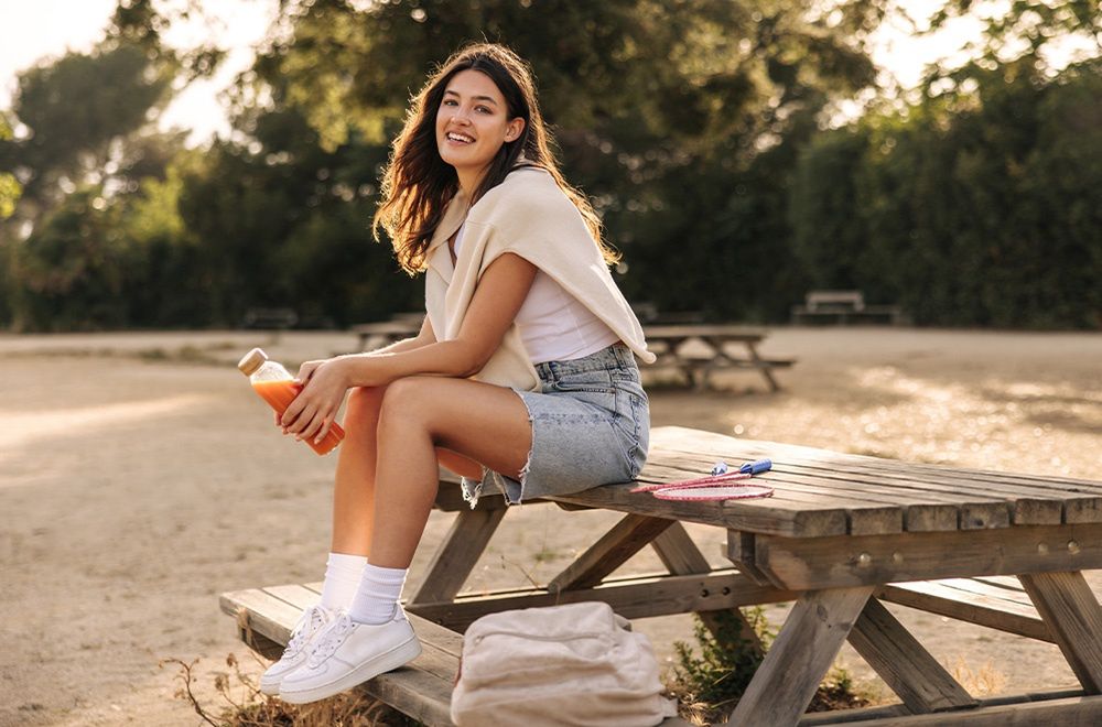 Dziewczyna siedząca na ławce w krótkich jeansowych spodenkach - zdjęcie.