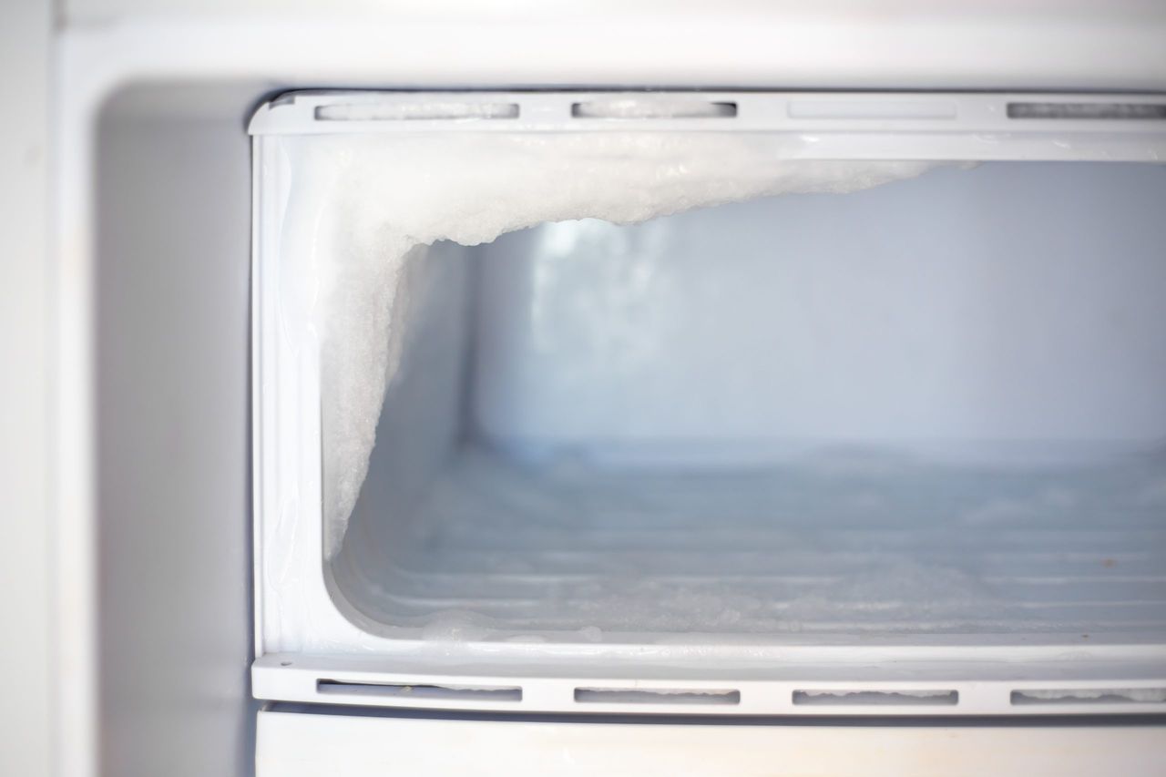 Fridge freezer with frozen ice. Maintenance and defrosting of the refrigerator.