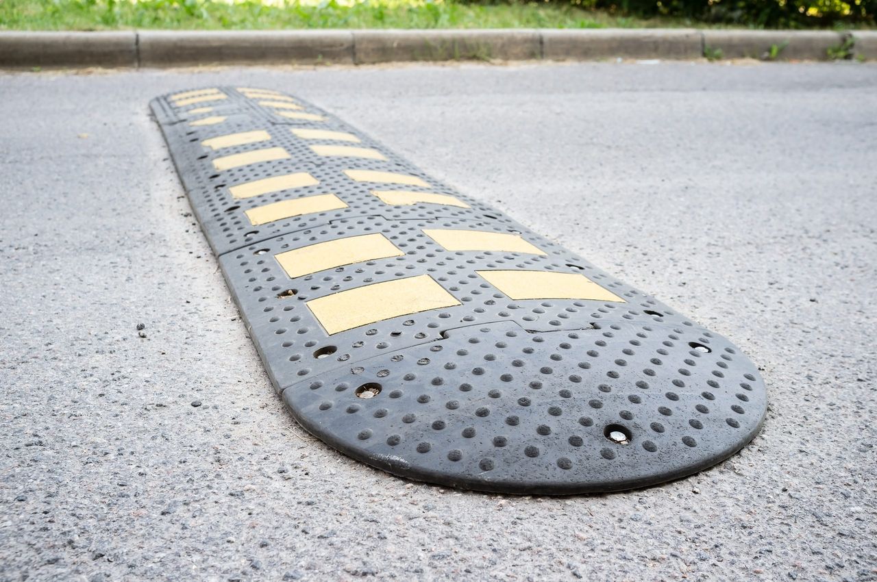 Yellow and black speed bumps on the asphalt road in the city. Obstacle in the path of vehicles to reduce the speed and safety of pedestrians.