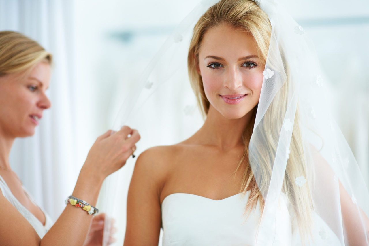 A young woman trying on wedding dresses in a bridal boutique.