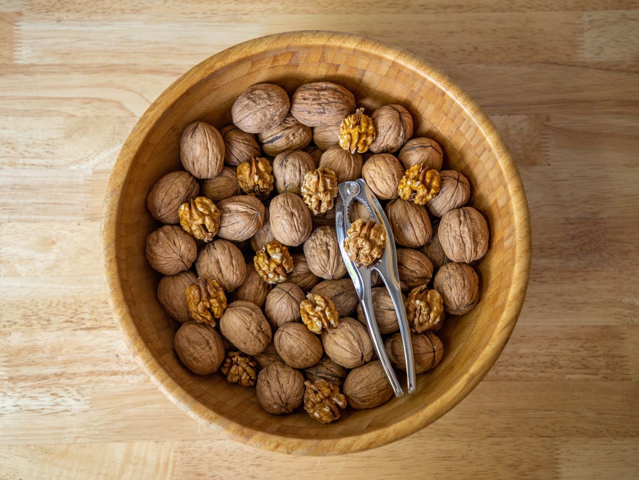 A closeup shot of walnuts in a brown bowl on wooden background