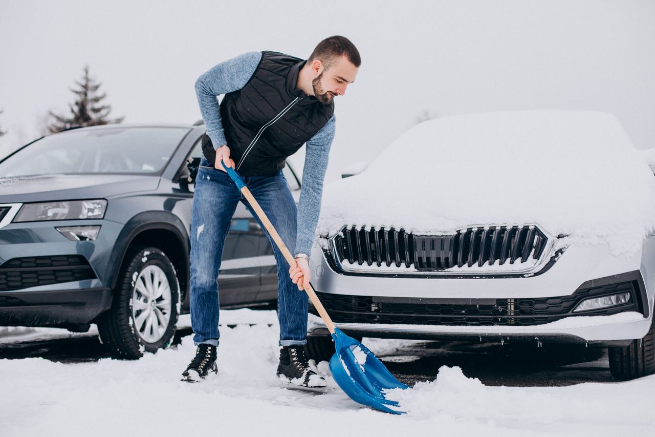 Man removing snow with shovel by the car