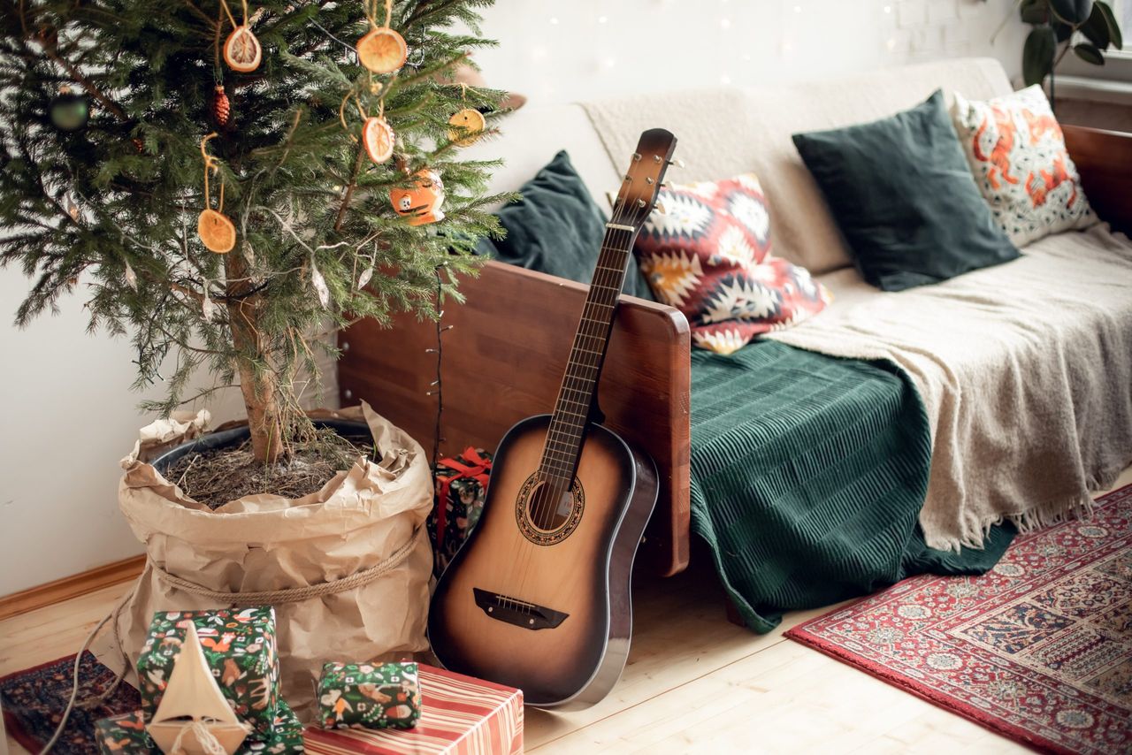 cozy vintage New Year's interior with a real live Christmas tree. loft, family celebration at home, dried oranges instead of toys, guitar, retro sofa with decorative pillows