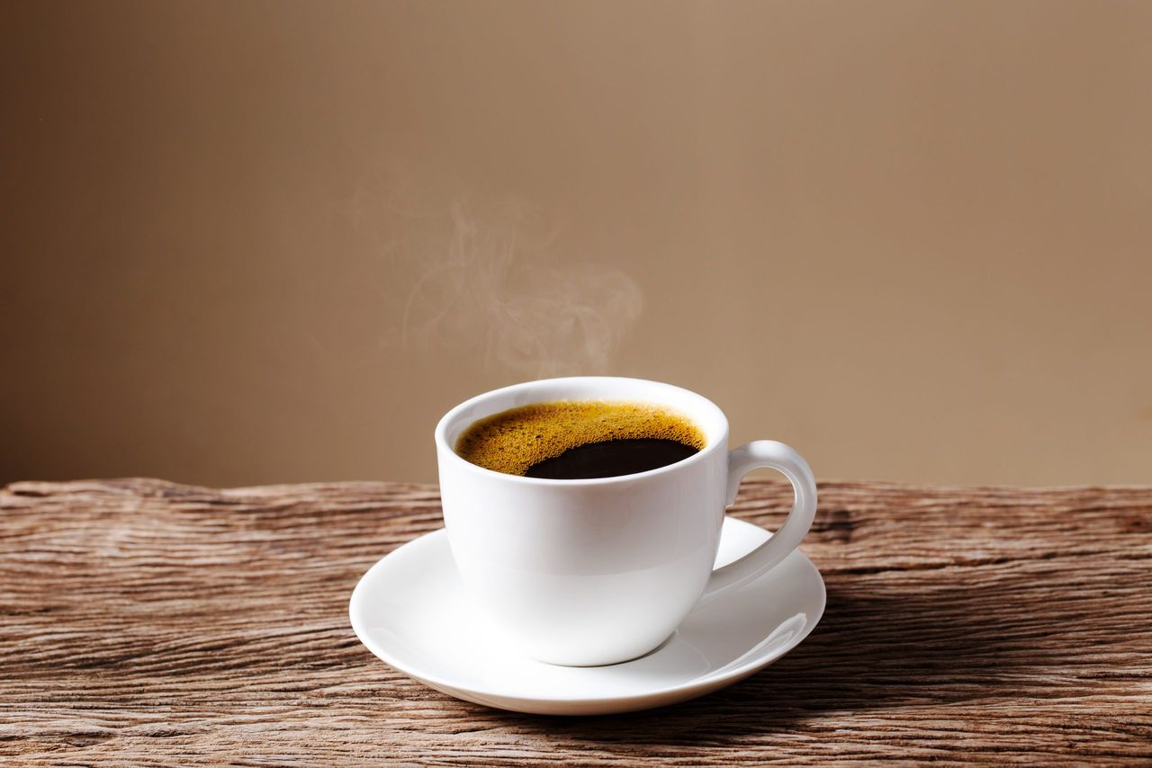 coffee cup on old wooden table with cream wall background.