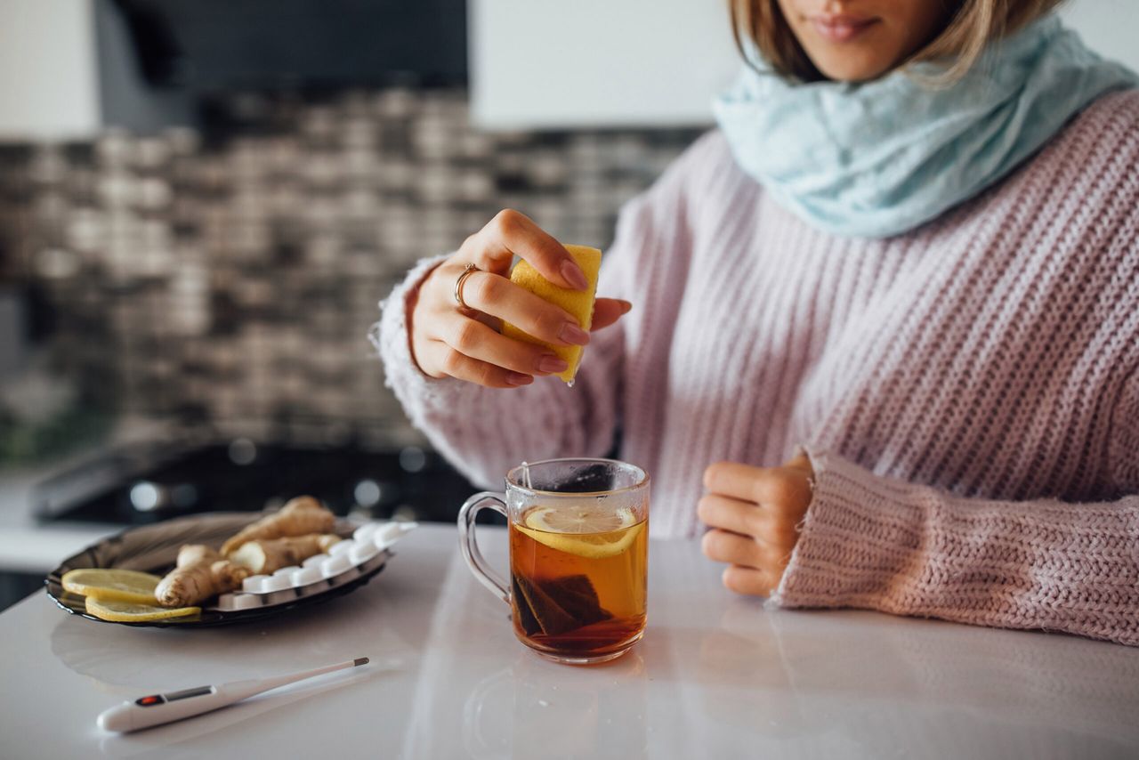 Close up photo,  female hands squeezing lemon to her tea.