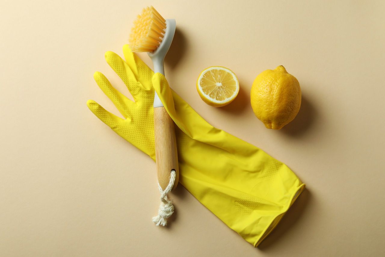 Glove with eco friendly brush and lemons on beige background