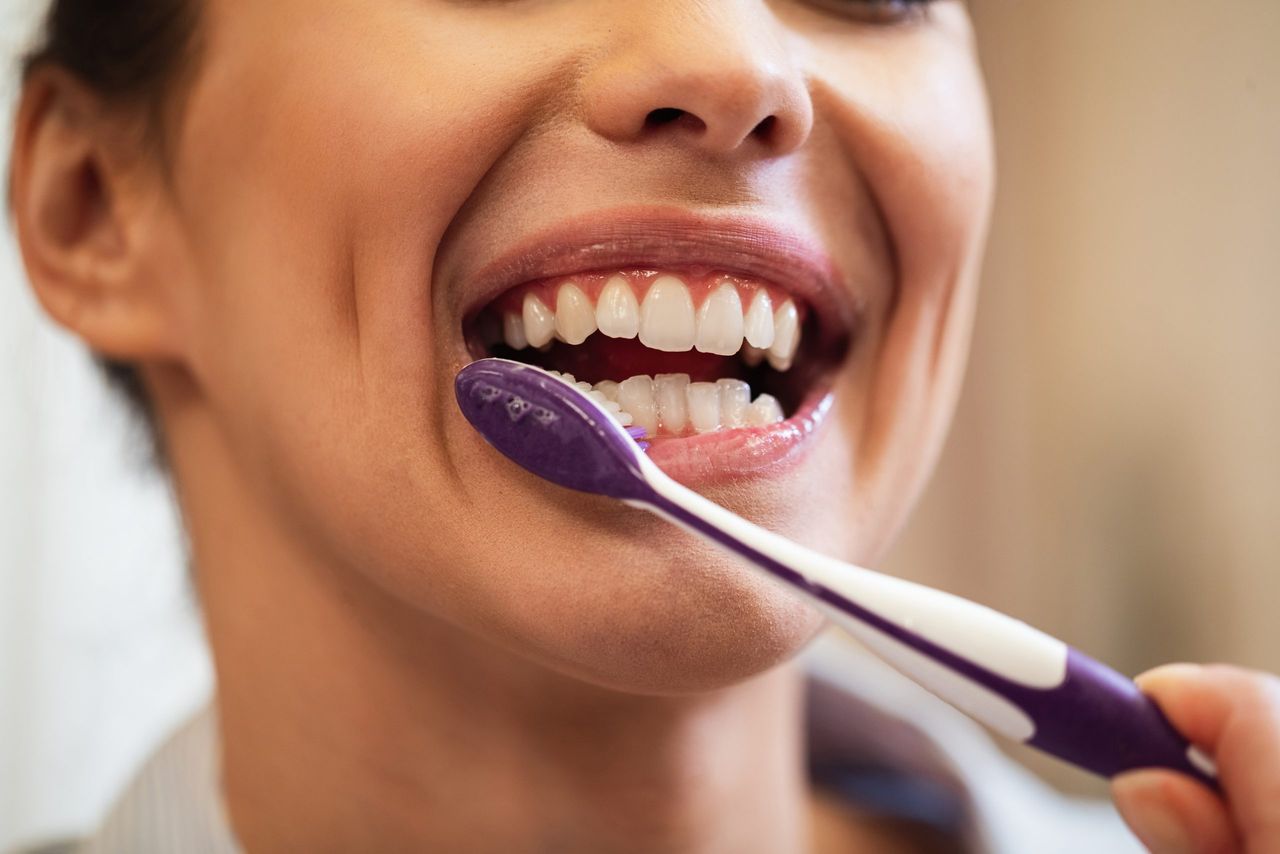 Close-up of woman using toothbrush while brushing teeth in the bathroom.