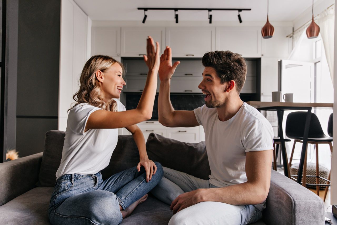 Stylish blonde girl playing with boyfriend in living room. Indoor photo of joking young people.