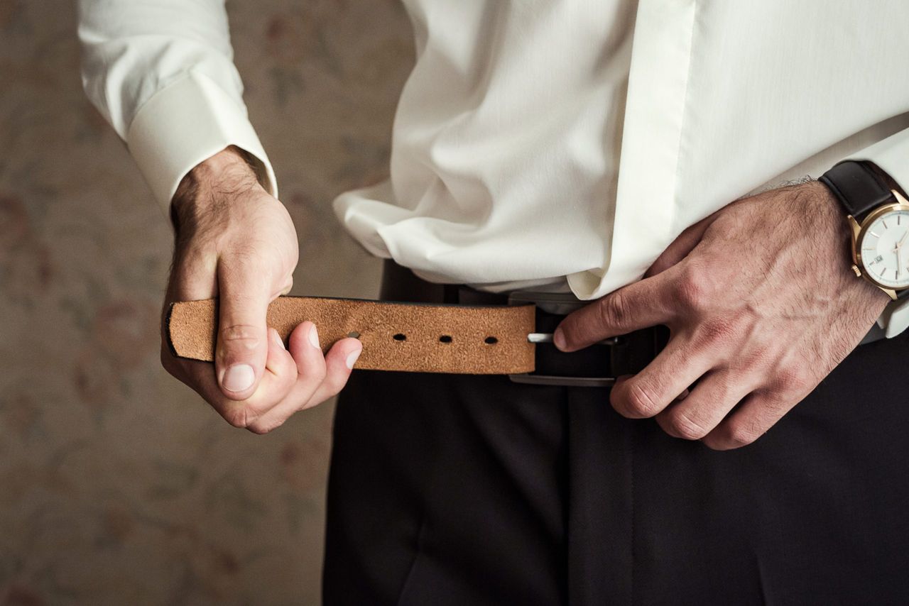 Businessman putting on a belt, fashion and clothing concept,groom getting ready in the morning before ceremony