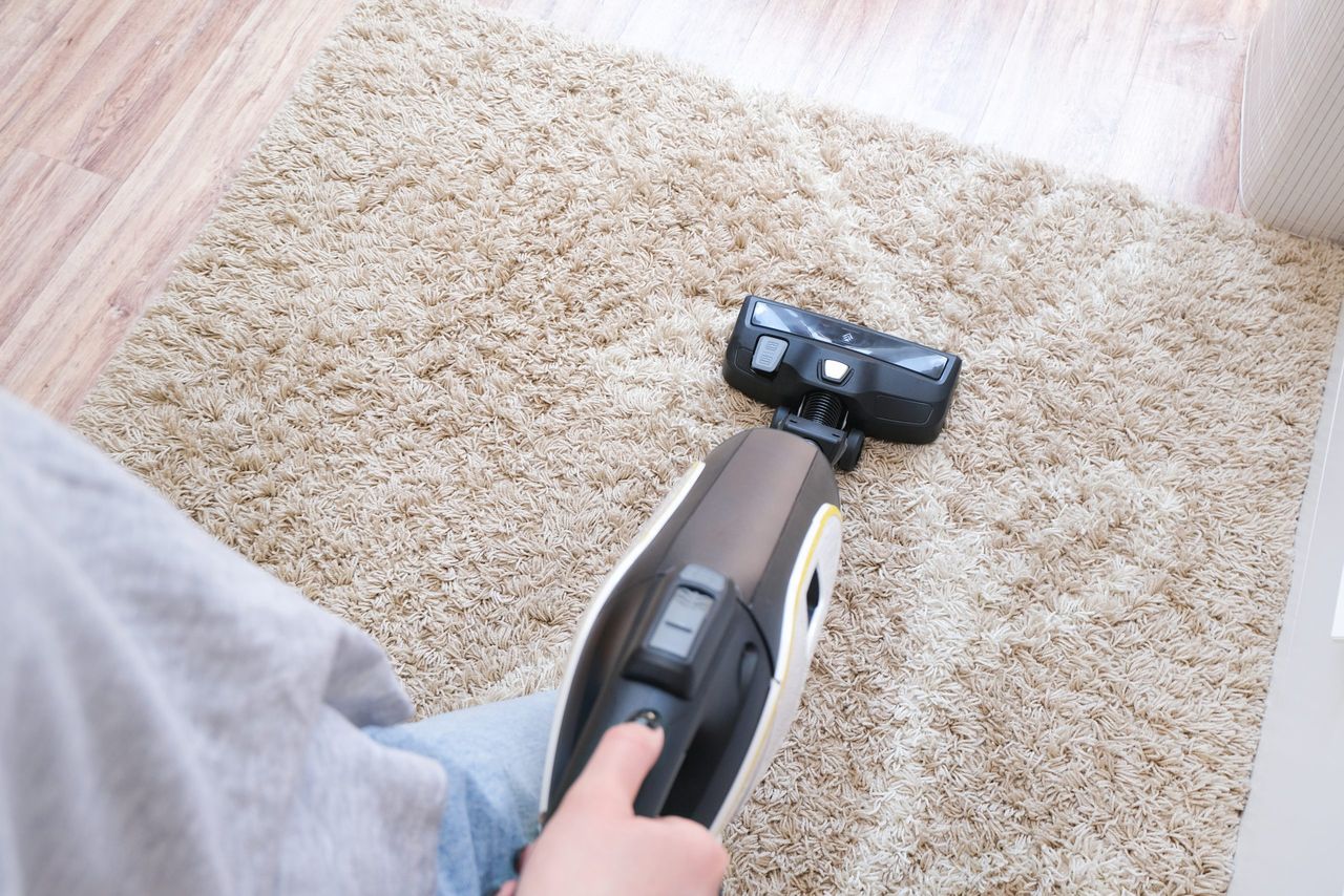 cordless vacuum cleaner is used to clean the carpet in the room. Housework with a new handheld vacuum cleaner. House cleaning, care and technology concept.