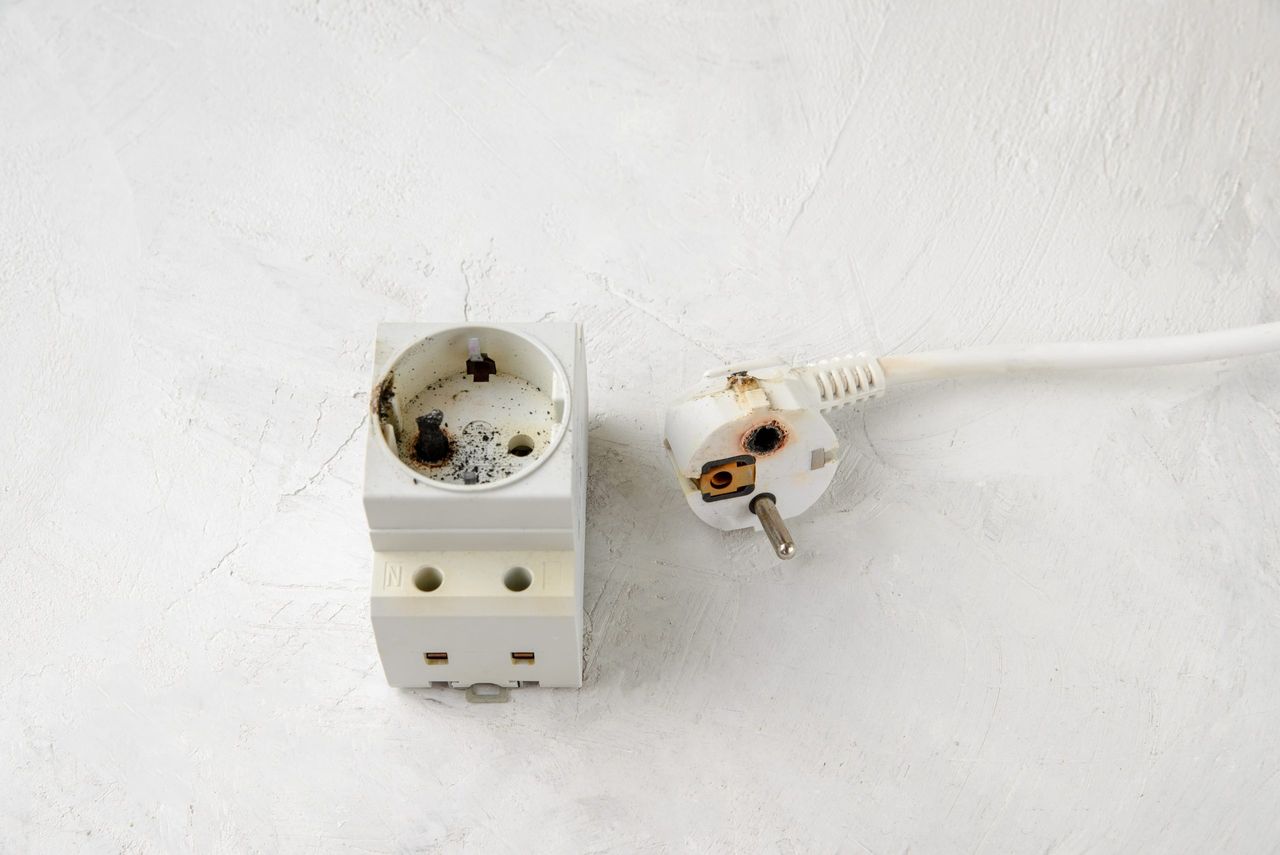 Old burnt plug and socket after a short circuit, Gray concrete background, close-up