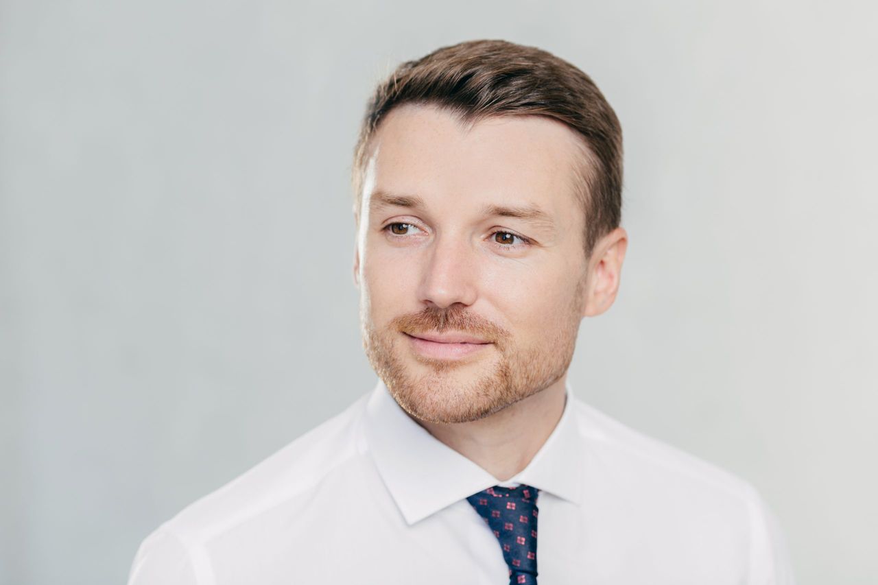 Close up portrait of handsome young man with stubble, looks pensively aside, thinks about something, dressed in formal clothes, isolated over white studio wall with copy space for your text.