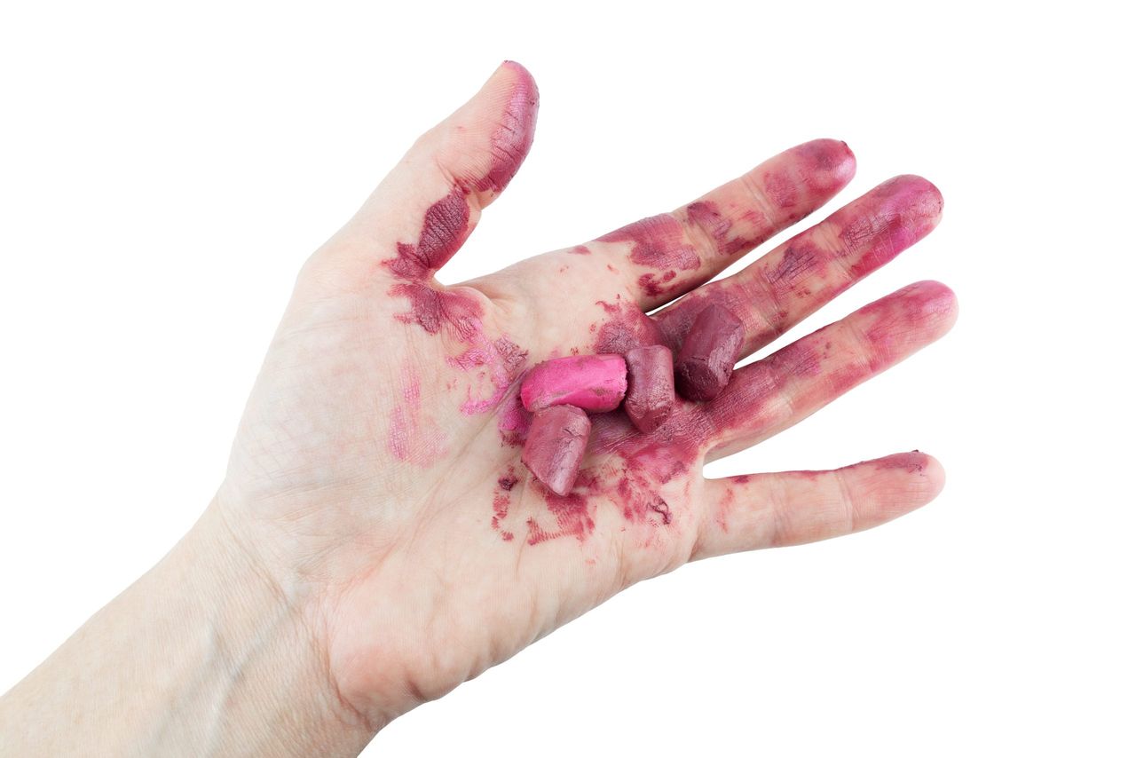 Smeared red lipstick on palm, isolated on white