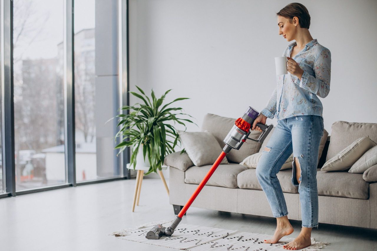 Woman with accumulator vacuum cleaner drinking coffee