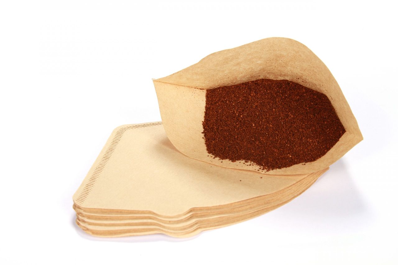 A pile of freshly ground coffee in a filter isolated on a white background