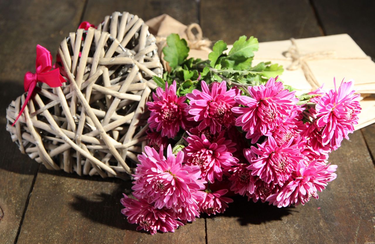Bouquet of pink chrysanthemum letters and hearts on wooden table
