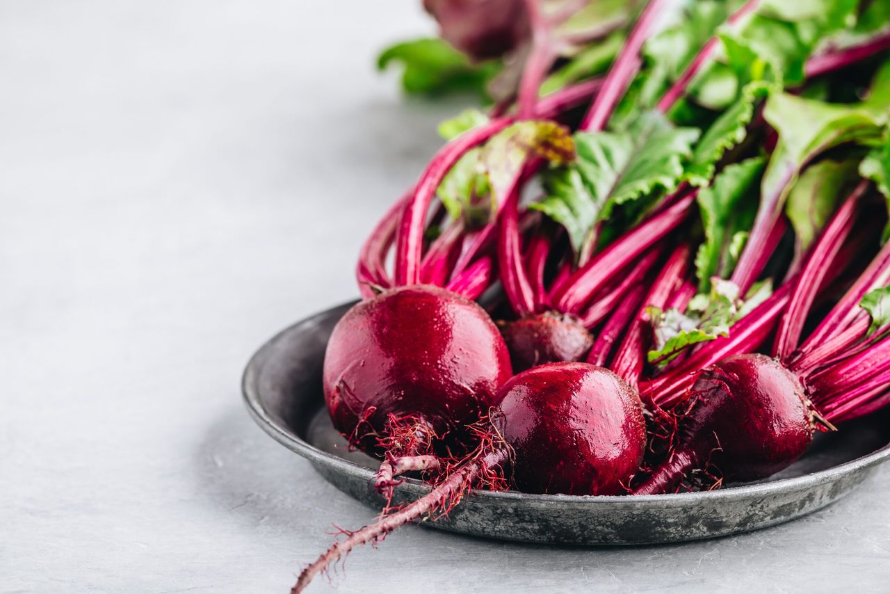 Bunch of fresh raw organic beets with leaves on a gray stone background