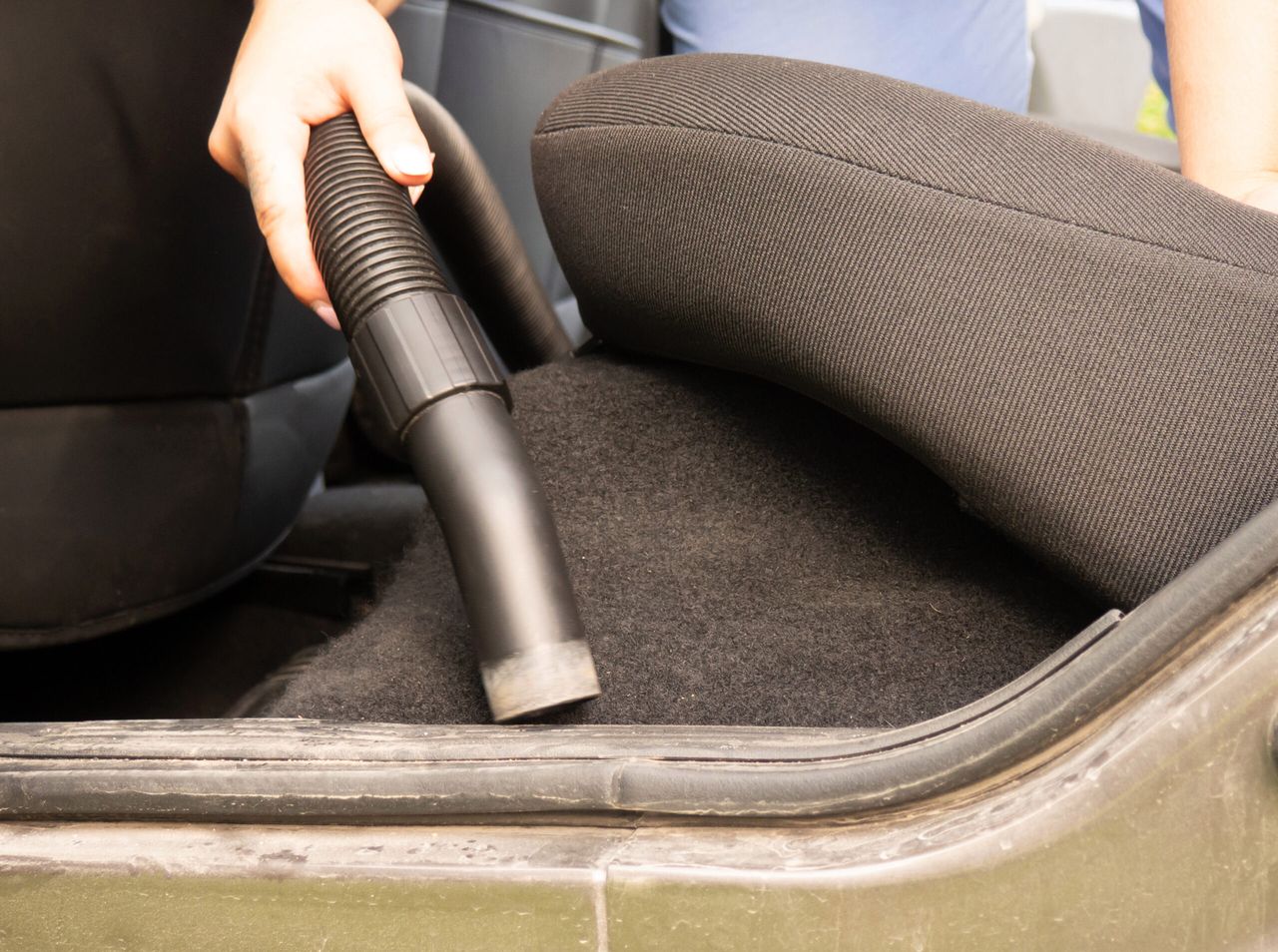 cleaning the car, the girl collects the crumbs with a vacuum cleaner in the car