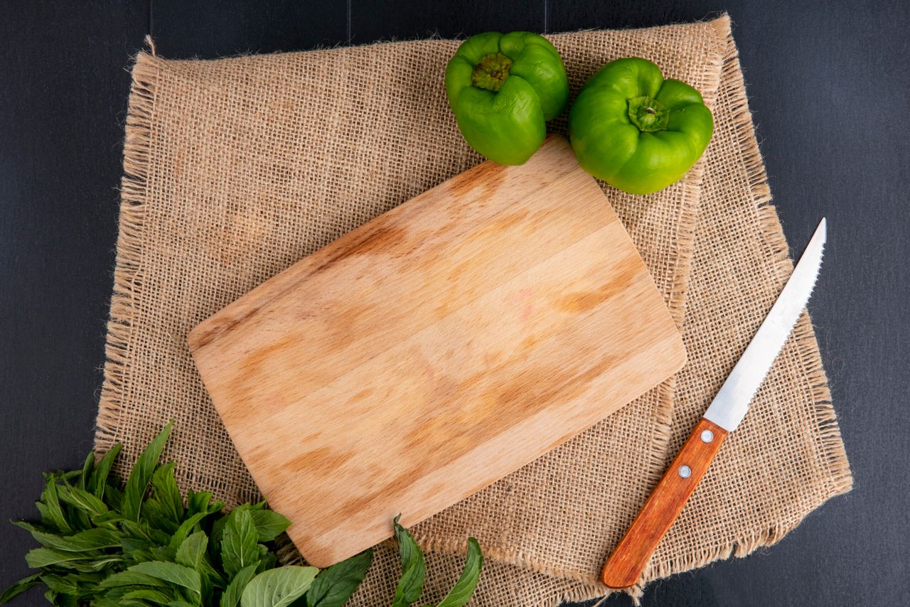 top view copy space cutting board with bell pepper knife and mint on a beige napkin