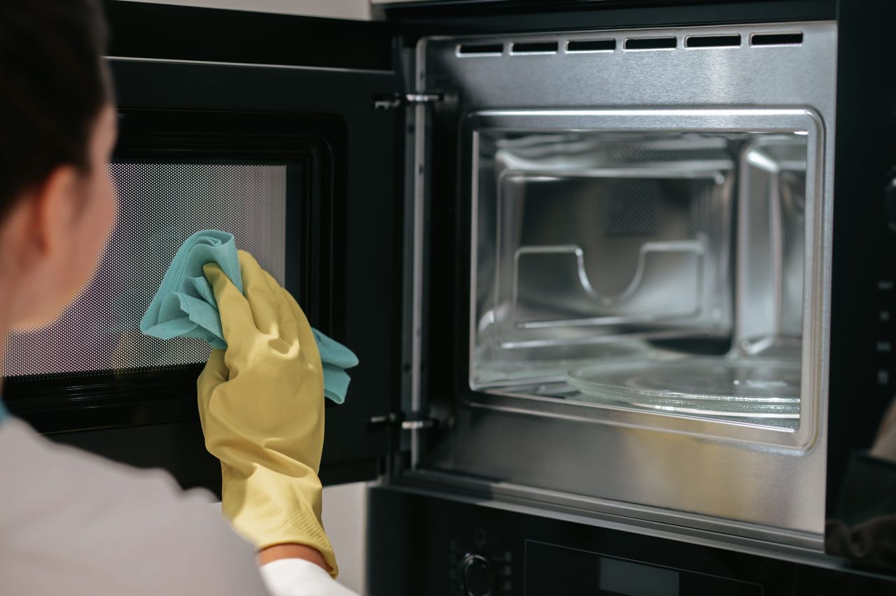Cleaning works. A woman in yellow gloves cleaning the oven