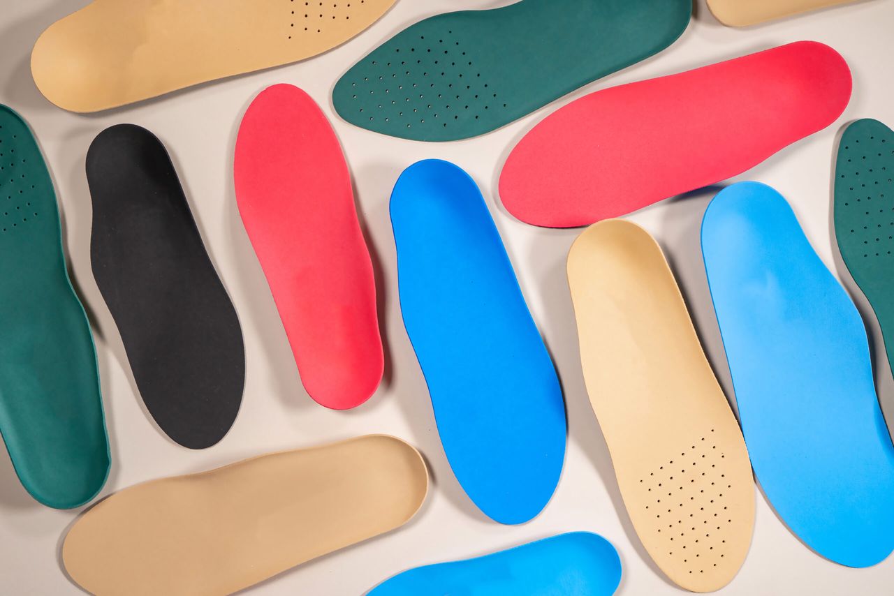 Orthopedic insoles are lined up on a wooden surface. samples of different orthopedic insoles. insoles with variety of coating.
