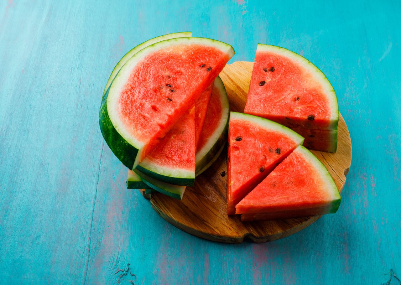 Delicious watermelon pieces on blue background, flat lay.