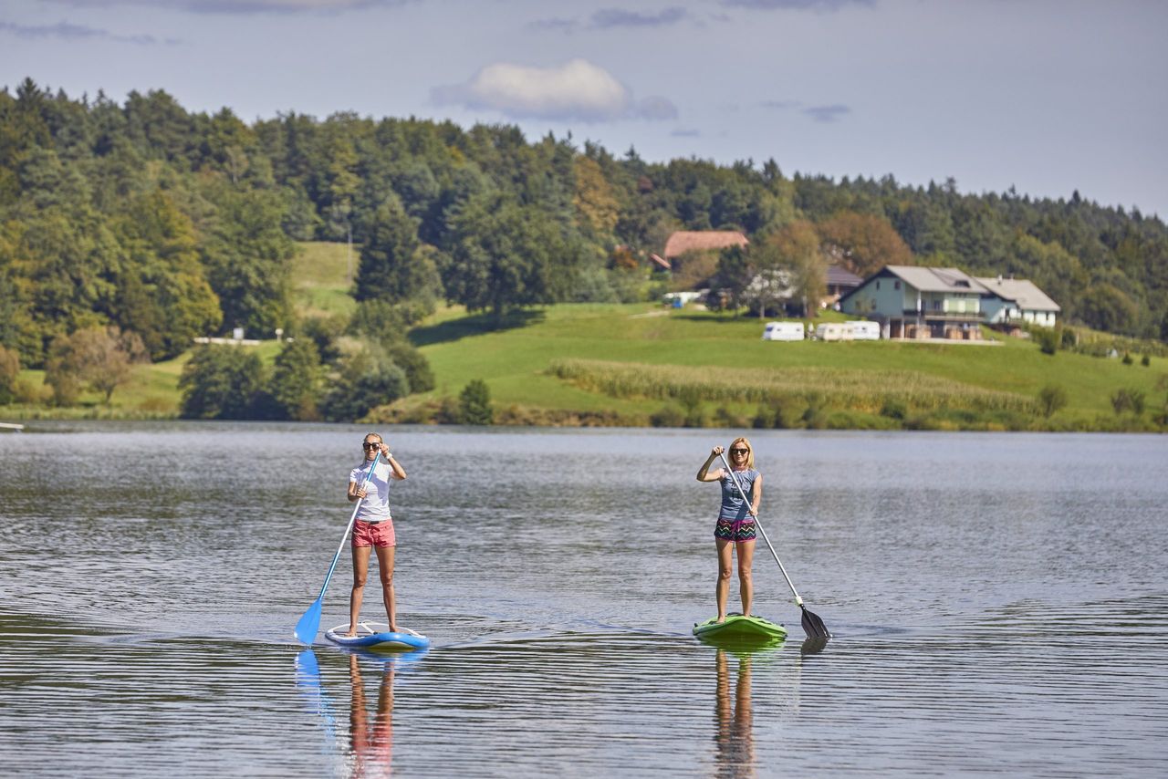 The two females riding a stand up paddle board in the Smartinsko lake in Slovenia