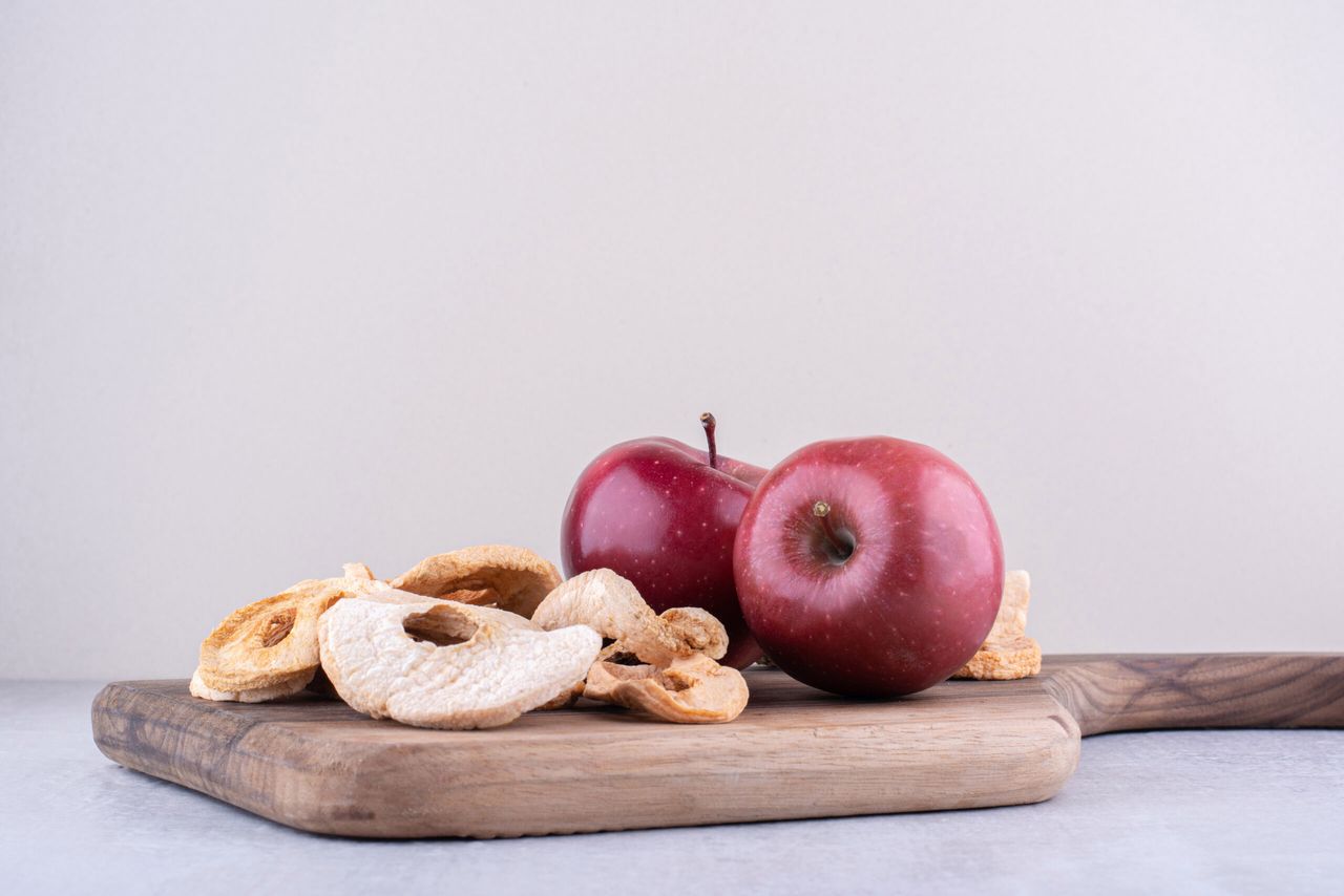 Apples and dried apple slices on a board on white background. High quality photo